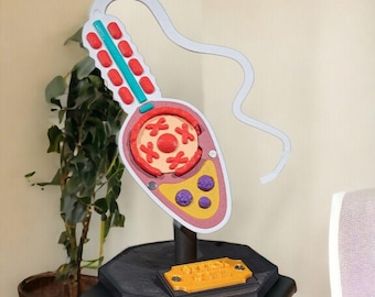 May include: A 3D-printed model of a sperm cell featuring a white tail, a light pink head with a teal stripe, red oval accents, a central circular section with red cross shapes, and a yellow base with three purple spheres on a black stand.