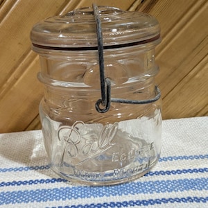 May include: A vintage clear glass Ball Eclipse jar with a wire bail closure. The jar has a textured surface and the words "Ball Eclipse" are printed on the side.