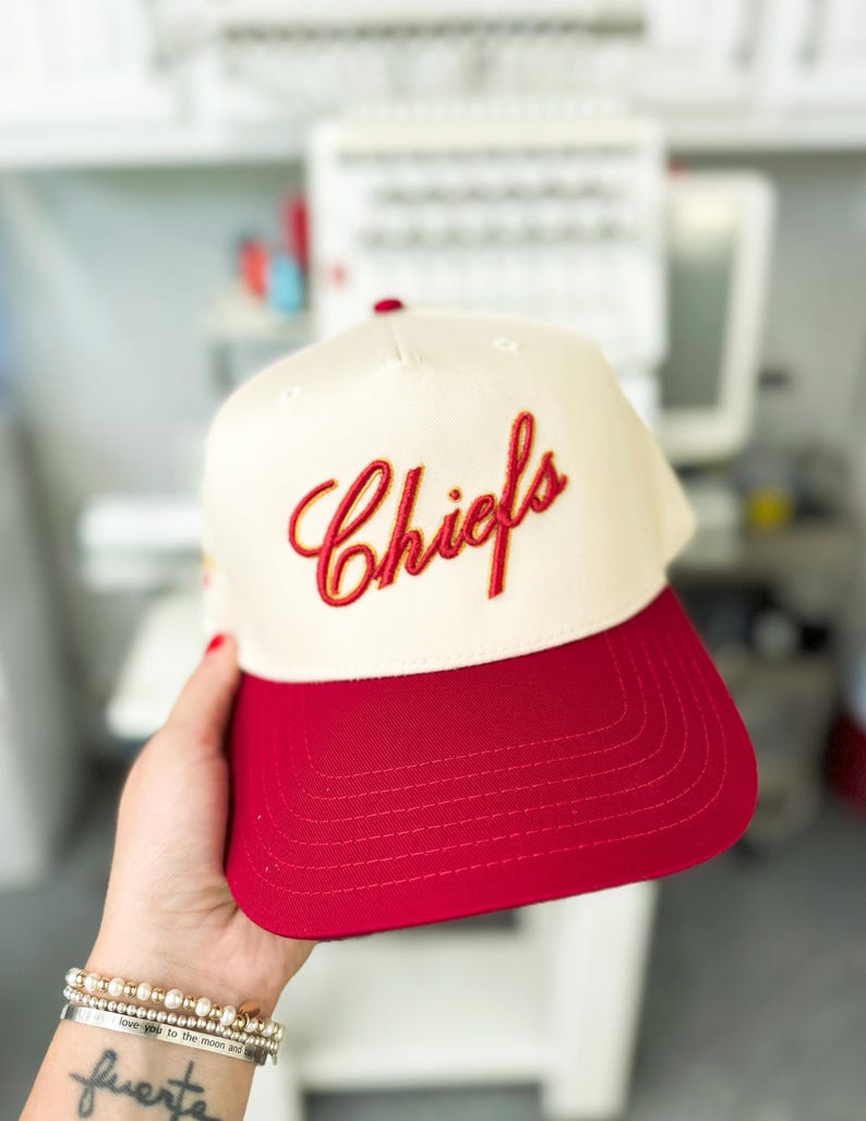 May include: A white and red baseball cap with the word "Chiefs" embroidered in red on the front.