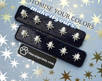 May include: Three dark blue wall-mounted key holders with white star-shaped key hooks. The key holders have a textured surface and are arranged on a light blue background with gold stars. The text "CUSTOMISE YOUR COLORS make it yours!" is visible.
