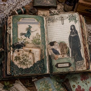 Pode incluir: Um di&aacute;rio de recortes aberto com p&aacute;ginas de estilo vintage, apresentando uma bruxa numa vassoura, uma figura encapuzada e um corvo. As p&aacute;ginas incluem bolsos com etiquetas bot&acirc;nicas, acabamentos em renda e um suporte de metal com o texto remember this.