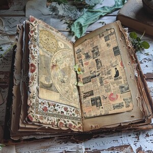 May include: An open vintage journal with brown leather covers and pages filled with old newspaper clippings and a hand-drawn map. The journal is decorated with lace and floral patterns.