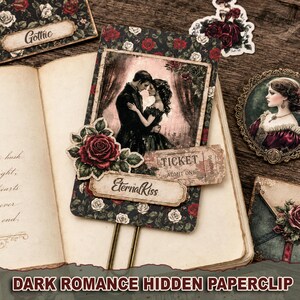 Pode incluir: Um clipe de papel decorativo com um cartão retangular de padrão floral escuro com rosas vermelhas e brancas. O cartão exibe uma ilustração de um casal, um recorte de rosa vermelha, um bilhete vintage com TICKET ADMIT ONE e um rótulo EternalKiss.