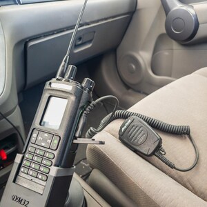 Puede incluir: Una radio de dos v&iacute;as negra con pantalla, teclado y antena montada en el portavasos de un coche. La radio est&aacute; etiquetada como "DM32" y tiene un micr&oacute;fono conectado etiquetado como "AnyTone".