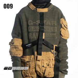 Könnte beinhalten: Ein grünes und braunes Sweatshirt mit einem schwarzen Gurt über der Brust. Das Sweatshirt trägt den Schriftzug "G-STAR ORIGINALS RAW DENIM" auf der Vorderseite.