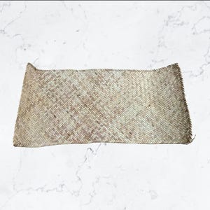 Puede incluir: Una cesta rectangular tejida, de color marrón claro natural. La cesta tiene una superficie texturizada y un borde superior ligeramente curvado. El patrón de tejido visible le da un aspecto rústico y hecho a mano. Probablemente utilizado para almacenamiento o decoración.