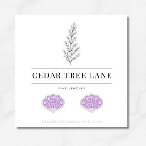 May include: Silver seashell stud earrings with lavender gems, presented on a white card. The card displays the text "CEDAR TREE LANE FINE JEWELRY" and the Etsy shop URL.