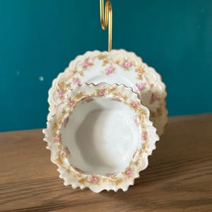 May include: A white ceramic mug with a black handle and the text "But First, Coffee" in a bold, black font. The mug is set against a blurred background, suggesting a cozy setting.