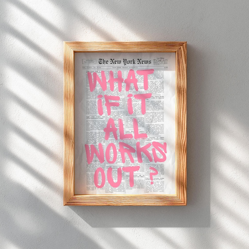 Puede incluir: Una impresi&oacute;n enmarcada que muestra una p&aacute;gina de peri&oacute;dico antigua con el texto WHAT IF IT ALL WORKS OUT? escrito en letras grandes, negritas y de color rosa brillante en el centro. El marco es de madera clara con veta visible.