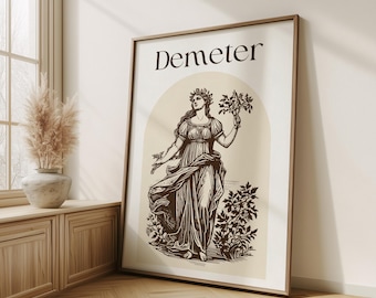 May include: A framed print featuring a black and white illustration of Demeter, the Greek goddess of agriculture, holding a sheaf of wheat. The print has a beige background with the word "Demeter" in brown text at the top.
