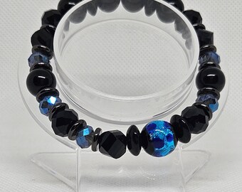 May include: Black and blue beaded bracelet with a large blue and silver patterned bead.