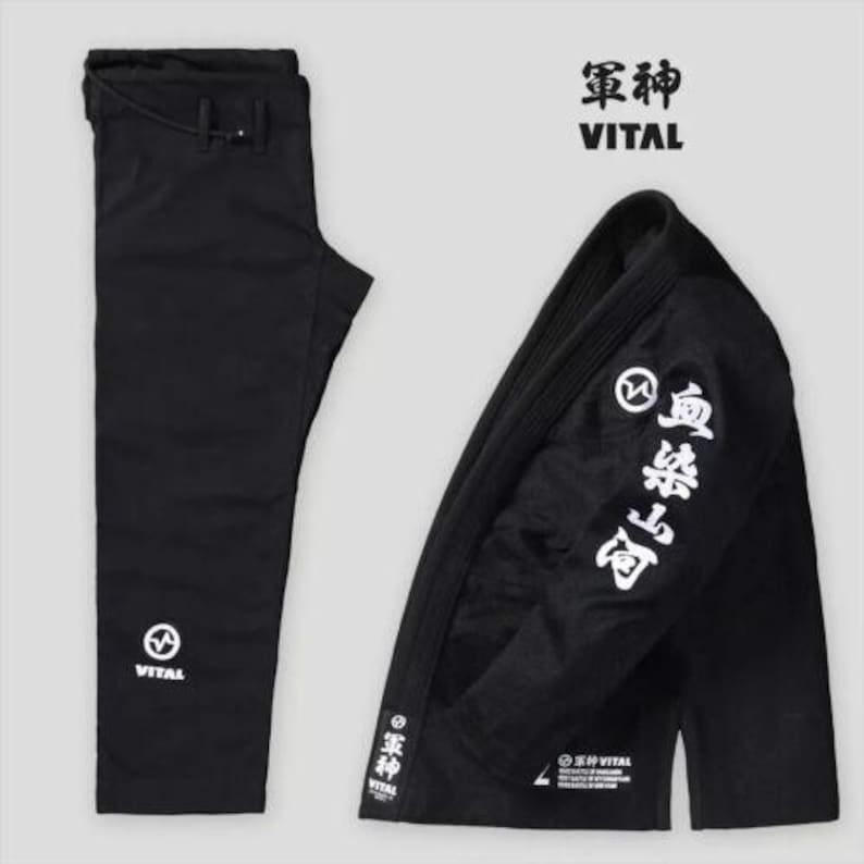 May include: Black Jiu-Jitsu Gi with white kanji writing on the sleeve and the word "VITAL" on the pants and jacket. The jacket has a white circle with a lightning bolt inside.