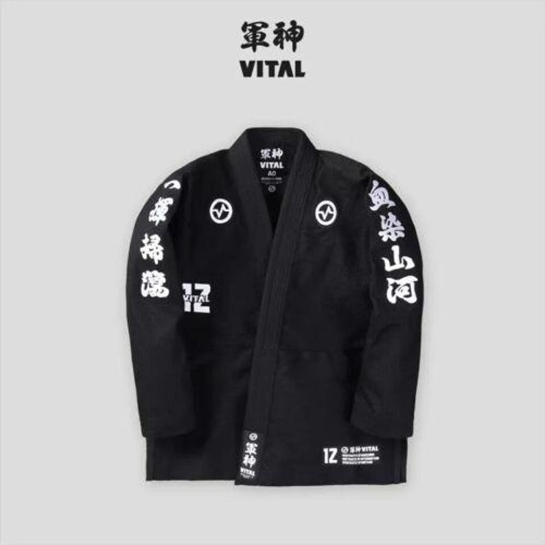 May include: Black martial arts uniform with white kanji characters on the sleeves and back. The uniform has a black belt and the text "軍神 VITAL" on the front.