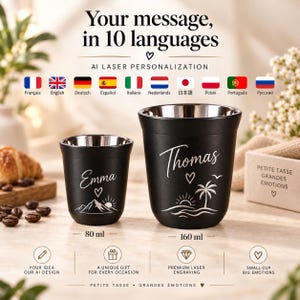 May include: Two black stainless steel cups with silver interiors. The smaller 80 ml cup features the name Emma, a heart, and a mountain graphic. The larger 160 ml cup features the name Thomas, a heart, a bird, and a palm tree over ocean waves.
