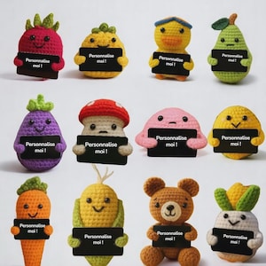 May include: A selection of twelve colourful, crocheted amigurumi figures, each holding a small black sign with the text "Personnalise moi!". The figures include fruits, vegetables, and animals, such as a pear, duck, and bear.