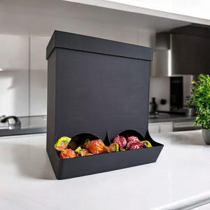 Peut inclure: Un distributeur noir avec deux ouvertures pour distribuer des bonbons. Le distributeur est rempli de bonbons colorés.