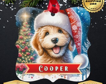 May include: A personalized Christmas ornament featuring a smiling, light brown dog wearing a Santa hat. The ornament has a red ribbon for hanging and the name "Cooper" on a red banner. The background includes a Christmas tree and falling snow.