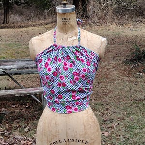 May include: A halter top with a blue and white gingham pattern and pink floral print. The top is on a dress form.