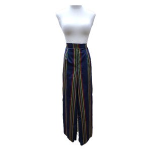 May include: Navy blue striped pants with vertical stripes in red, yellow, and green. The pants are displayed on a white mannequin. The pants have a high waist and a split front design.