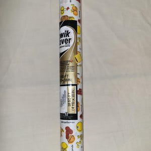 May include: A roll of white decorative adhesive plastic with a fruit pattern. The roll features illustrations of bananas, apricots, cherries, pineapples, lemons, almonds, and strawberries. The text "wik over" is visible, along with the dimensions of 18 sq ft (4 yd x 18 in).