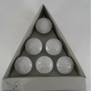 May include: Six white ceramic cabinet knobs with a textured swirl pattern. The knobs are arranged in a triangular pattern on a gray background.