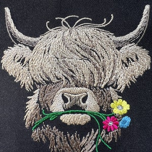 May include: Embroidered design of a Highland cow with brown fur, a white face, and a green stem with pink, yellow, and blue flowers in its mouth.