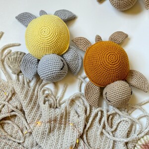 May include: Two crocheted turtle toys. One is yellow and the other is orange. Both have beige shells and gray faces.
