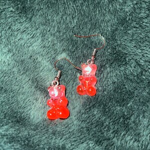 May include: A pair of pink gummy bear dangle earrings with silver hooks.
