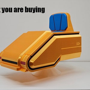 Pode incluir: Uma cadeira de estilo futurista de cor dourada com um assento azul. A cadeira está sobre uma superfície branca.