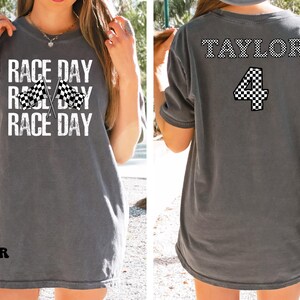 Pu&ograve; includere: Maglietta grigia con il testo "Race Day" e bandiere a scacchi. La parte posteriore della maglietta ha il testo "Taylor 4" in font a scacchi.
