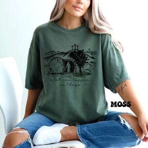 May include: A green t-shirt with a black graphic of a stone tomb, a cross, and the text "a lot can happen in 3 days".