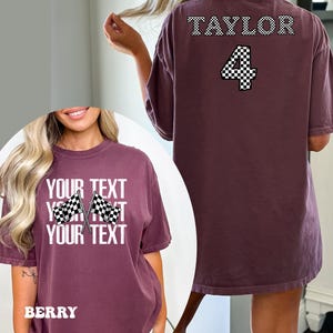 Pu&ograve; includere: Maglietta oversize color borgogna con un design a bandiera a scacchi e il testo "YOUR TEXT YOUR TEXT YOUR TEXT" sul davanti. La parte posteriore della maglietta ha il testo "TAYLOR" e il numero "4" in un design a bandiera a scacchi.
