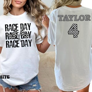 Pu&ograve; includere: Maglietta bianca con il testo "RACE DAY" ripetuto tre volte e una grafica di bandiera a scacchi. La parte posteriore della maglietta ha il testo "TAYLOR" e il numero "4" in uno schema a scacchi.