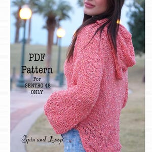 May include: PDF pattern for the Sentro 48 crochet sweater. The sweater is a light pink color with a speckled pattern and a hood. The sweater is shown on a model wearing blue jeans.