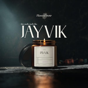 May include: A lit brown glass candle jar with a black lid, labeled "JAYVIK" with the text "this candle smells like" above. The candle is on a dark surface with the brand name "HausofSnow" at the top.