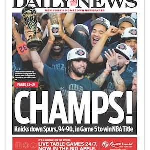 May include: A Daily News newspaper front page dated June 14, 2026, featuring a photograph of basketball players celebrating with a trophy. The headline reads CHAMPS! and Knicks down Spurs, 94-90, in Game 5 to win NBA Title. Includes sports news.