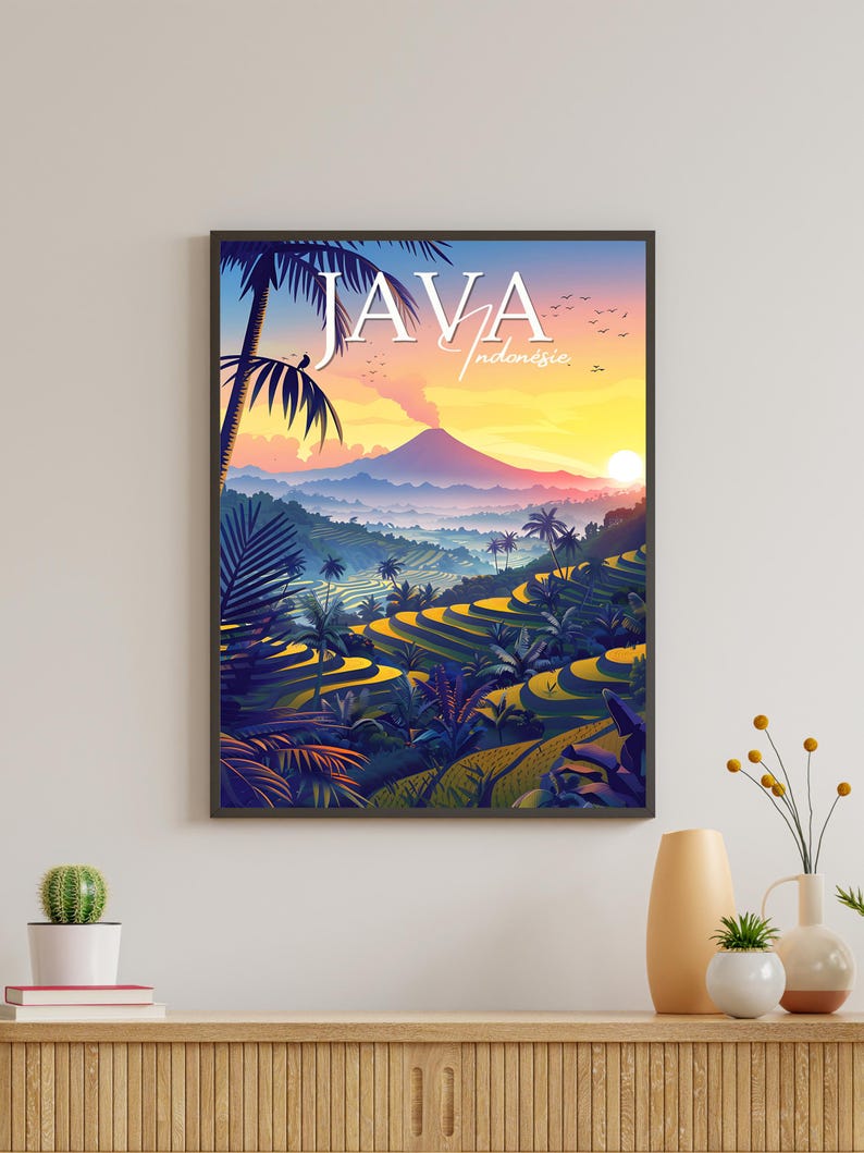 Pu&ograve; includere: Un poster colorato con il testo "JAVA Indonesia" in una cornice nera. Il poster presenta un paesaggio panoramico con una montagna, risaie e palme. Il cielo &egrave; di un arancione e rosa vibrante.