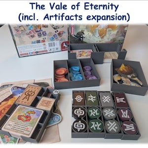 Könnte beinhalten: Das Brettspiel The Vale of Eternity mit der Erweiterung Artifacts. Das Bild zeigt die Spielbox, graue Aufbewahrungsschalen, Karten und Spielsteine. Die Schalen enthalten verschiedenfarbige Spielsteine und Karten mit Symbolen.