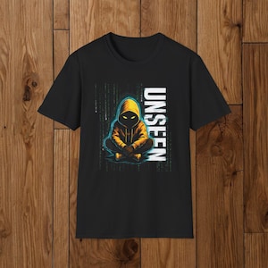 May include: Black t-shirt featuring a graphic of a hooded figure in yellow and black, with the word "UNSEEN" in white. The figure is seated with legs crossed. The background has a matrix-like design.
