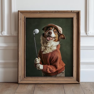 以下が含まれることがあります： オレンジ色のセーターとベージュのキャップを着て、ゴルフクラブとボールを持っている犬の額装された肖像画。犬は茶色と白の毛皮で、笑顔です。背景は濃い緑色です。