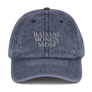 Könnte beinhalten: Eine dunkelblaue Baseballkappe aus Denim mit dem in Weiß gestickten Text "BADASS BONUS MOM" auf der Vorderseite.