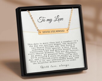 May include: A gold necklace with a bar pendant engraved with the date "XXVIII.VIII.MMXXI" and the words "To my Love" on a white card with a message about love and a shared journey.