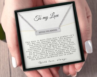 May include: A silver necklace with a bar pendant engraved with the date "XXVIII.VIII.MMXXI" and the text "To my Love" in a black box. The text below the pendant reads "This date is more than just a number - it's the day our journey began, the moment two hearts became one. Our bond is something truly special, a love that transcends time and grows deeper with every shared moment. You are my forever, my peace, my greatest love. Together, we've created a story as unique as this day, and I cherish every chapter we write. Here's to us, our unbreakable bond, and the beautiful memories yet to come. With love, always."