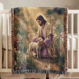 Könnte beinhalten: Eine gewebte Wohndecke mit der Darstellung einer bärtigen Figur in einem hellen Gewand und einer violetten Tunika, die in einem Blumenfeld kniet und ein kleines weißes Lamm hält. Die Decke hat einen Fransenrand und eine strukturierte Oberfläche.