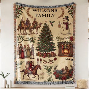 Könnte beinhalten: Eine gewebte Wohndecke mit cremefarbenem Hintergrund und dem Text "WILSONS FAMILY" über einem Weihnachtsbaum, einem Schneemann, den Heiligen Drei Königen auf Kamelen, einem Kamin mit Strümpfen, einer Krippe und dem Weihnachtsmann auf einem Pferd.