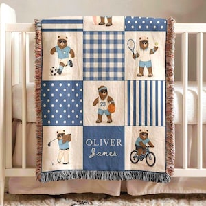 Puede incluir: Una manta para bebé con un diseño de patchwork que presenta osos de dibujos animados practicando deportes. La manta tiene una combinación de colores azul y blanco con flecos. El nombre "Oliver James" está en la manta.
