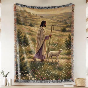 Könnte beinhalten: Eine gewebte Wandteppich-Decke mit der Darstellung einer Figur in einem hellen Gewand und violettem Untergewand, die mit einem Holzstab durch ein Feld mit Wildblumen neben einem kleinen weißen Lamm geht, mit gefransten Rändern versehen.