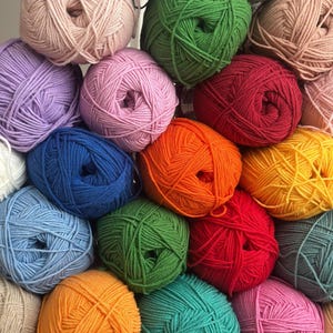 May include: A collection of colorful yarn balls in various shades, including pink, green, blue, orange, and yellow. The yarn is tightly wound, creating a textured surface. Ideal for knitting and crochet projects.
