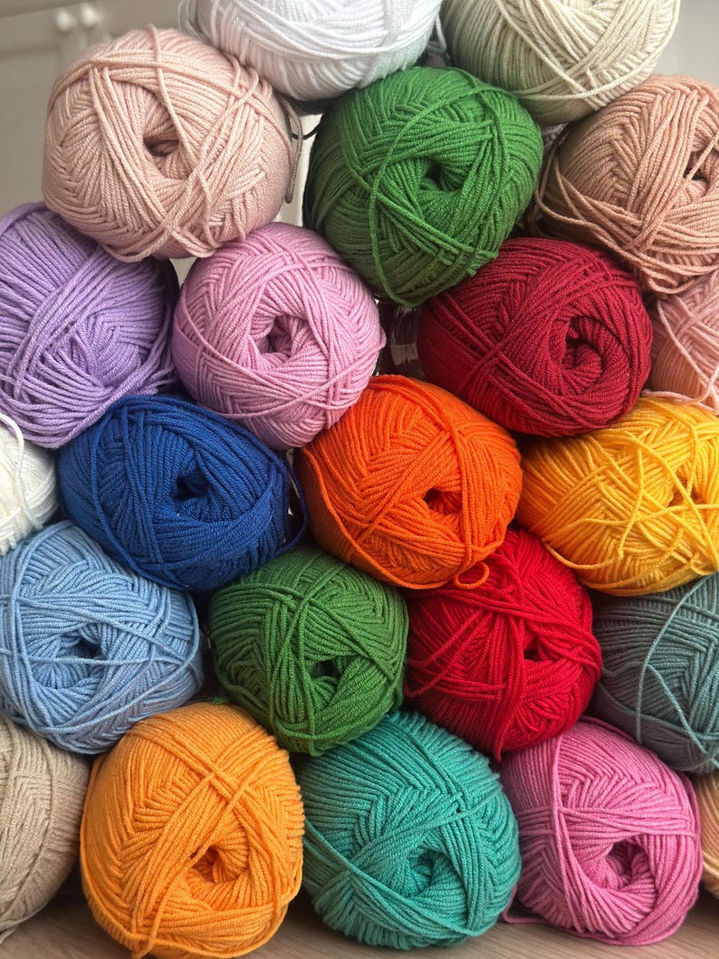 May include: A collection of colorful yarn balls in various shades, including pink, green, blue, orange, and yellow. The yarn is tightly wound, creating a textured surface. Ideal for knitting and crochet projects.