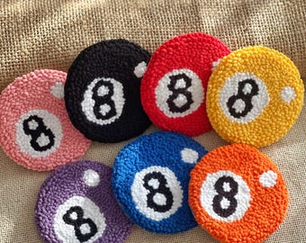 Può includere: Un set di sette sottobicchieri rotondi e colorati, ognuno con il design di una palla da biliardo numero 8. I sottobicchieri sono in vari colori, tra cui rosa, nero, rosso, giallo, viola, blu e arancione, con un numero 8 bianco.